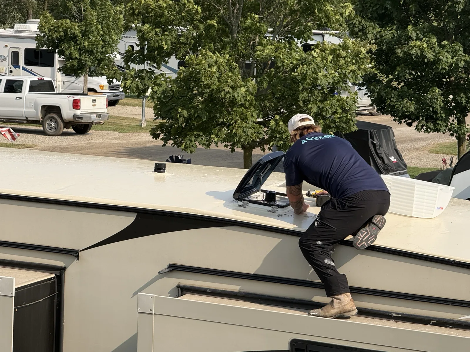 AquaRV technician inspecting and repairing an RV roof near a rooftop hatch